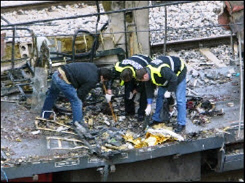 Agentes policiales rebuscan en el centro del foco. Uno de ellos sostiene una bolsa azul