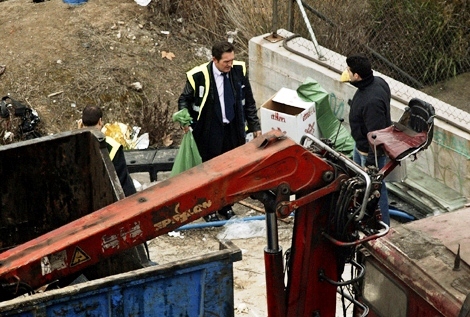 Junto a un camión con grúa, policías con bolsas