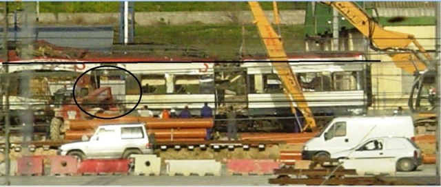 El coche 1 está siendo seccionado en dos partes y, probablemente, en tres. Tras efectuar el corte, la pluma de una excavadora levanta la parte de la derecha, mientras otra máquina sujeta el centro del coche. La línea negra horizontal pone de manifiesto que ya se ha empezado a levantar la parte de la derecha